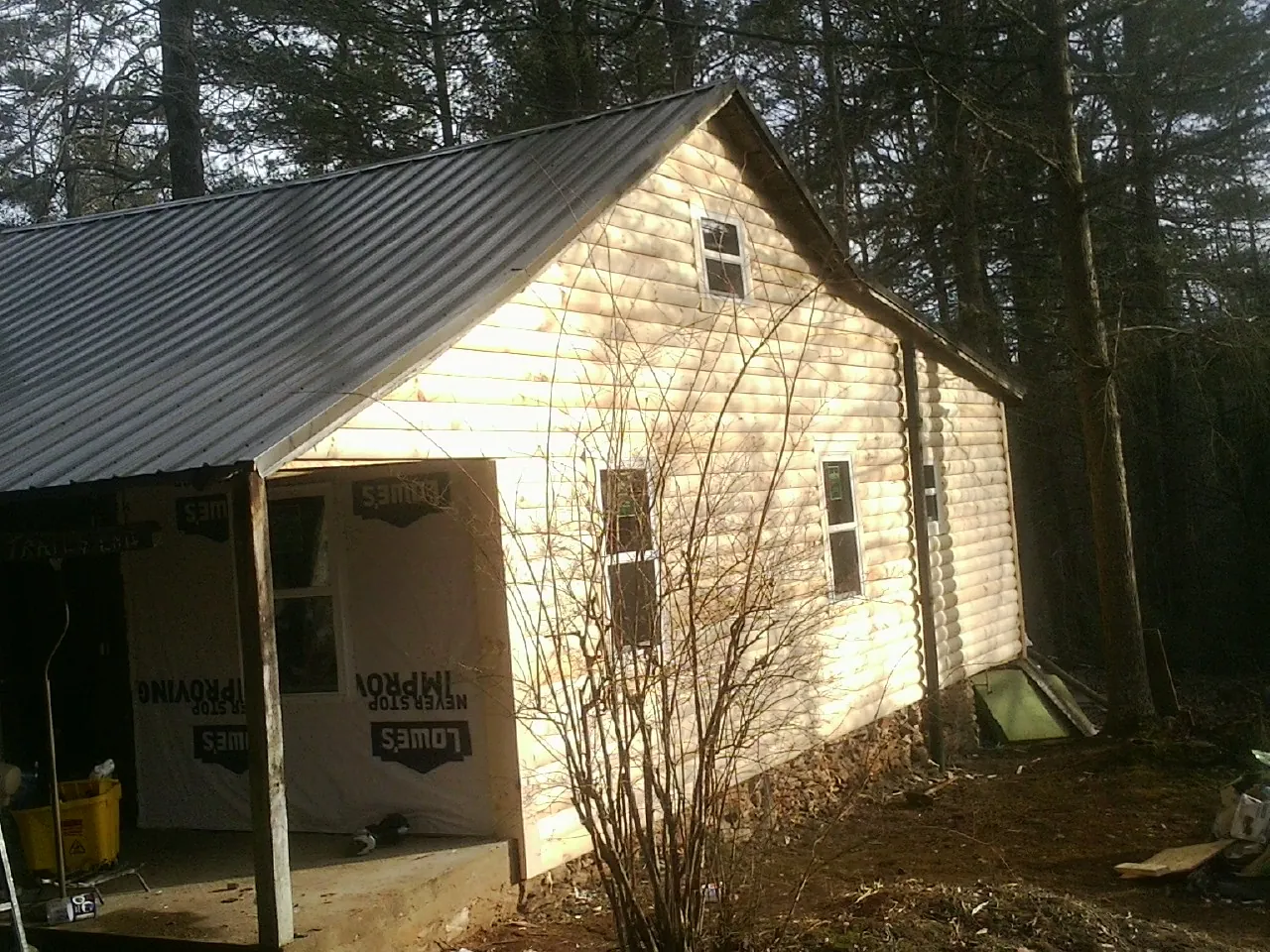 Log siding gable end under a dark metal roof edge in Croghan