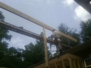 Carpenter setting a ridge beam over a new addition frame — Ice Dam Removal by Roofing Brothers in Croghan