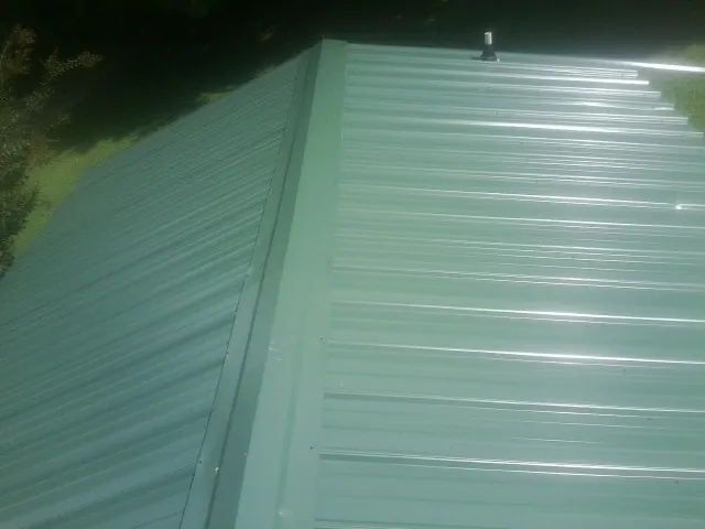 New green metal panels meeting at the ridge of a roof — Flat Roof Repair work by our crew in Croghan