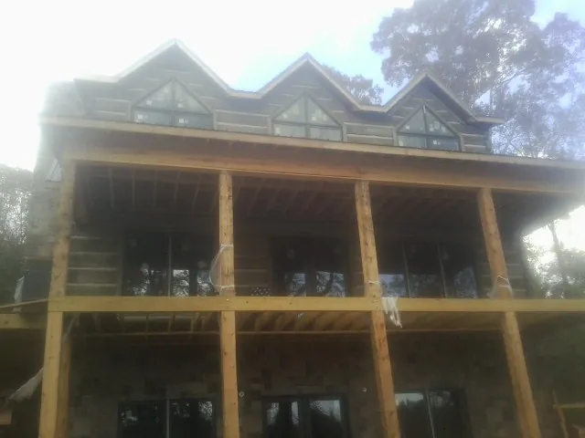 Dormers and porch framing on a large log home under construction — Roof Coating work by our crew in Croghan