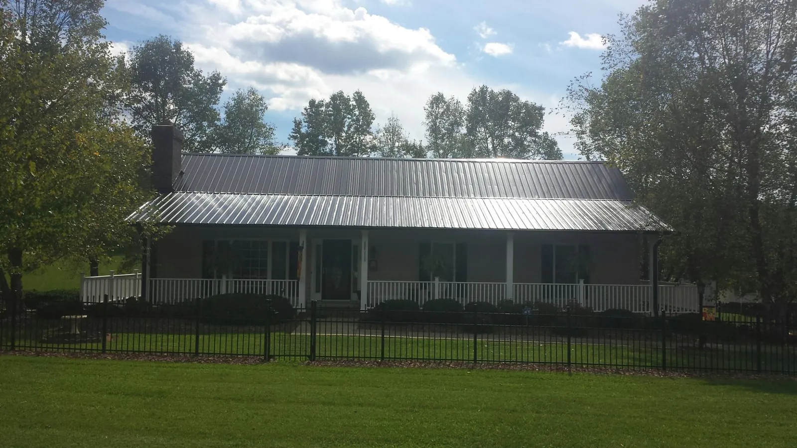 Gray metal roof on a brick ranch with a full width front porch — Gutter Guard Installation work by our crew in Croghan