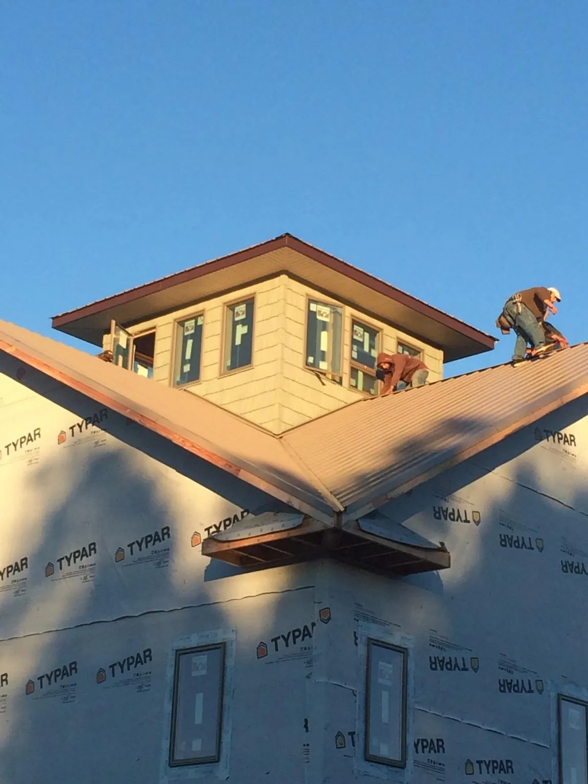 Roofers working around a rooftop cupola on a new metal roof at sunset — Roof Waterproofing in Croghan by Roofing Brothers